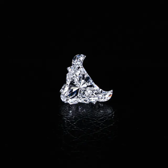 Heart-shaped diamond displayed on a dark reflective surface highlighting its brilliance.