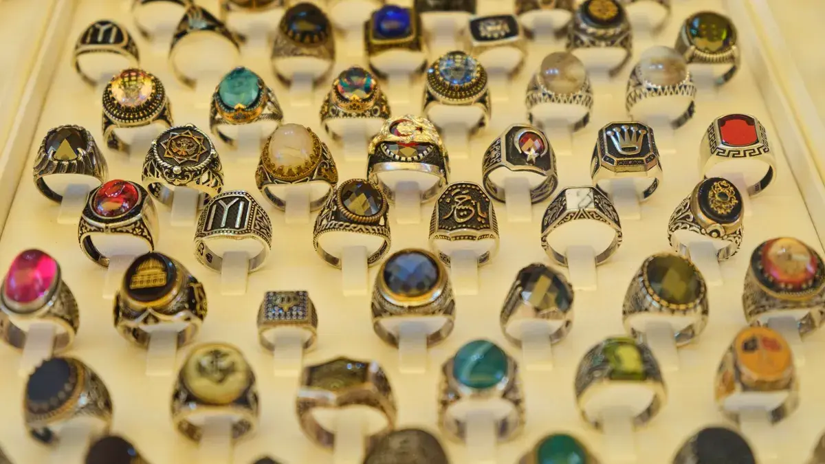 Close-up of assorted gemstone rings in a display case, showcasing intricate design and vibrant colors.